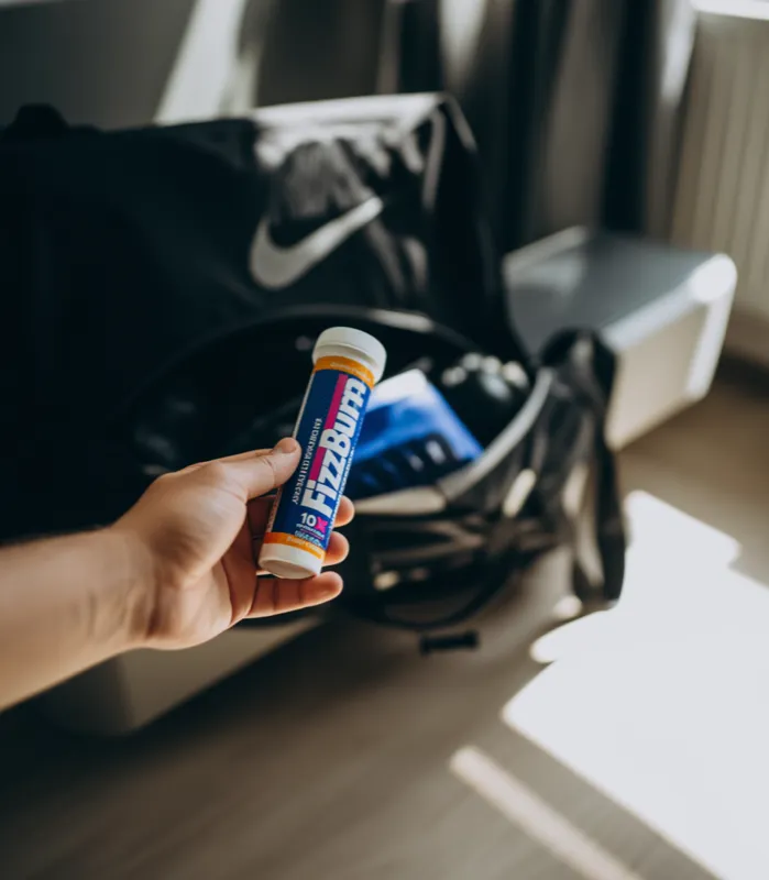 FizzBurn suplement diety w dłoni przed torbą sportową - Stenka Clinic